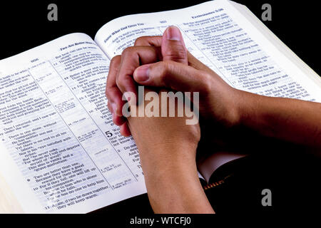 Asian womans mani giunte in preghiera sulla Bibbia aperta Foto Stock