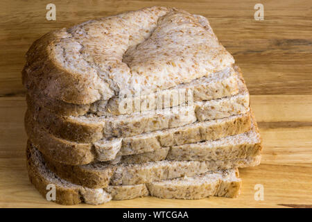 Pila di pane integrale le fette su un pane in legno board Foto Stock