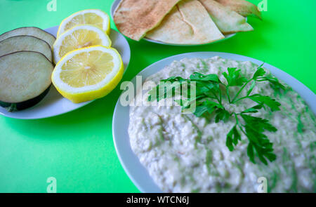 Famoso e tradizionale cucina araba - dip baba ganoush con pane pita e limone fresco su sfondo verde. Appartamento laico, vista dall'alto. Baba ganoush. Foto Stock