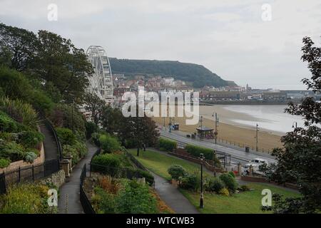 Vista dal parco di Victoria a sud sabbie della baia di Porto Faro e la grande ruota con pioggia in Scarborough Yorkshire Inghilterra Foto Stock