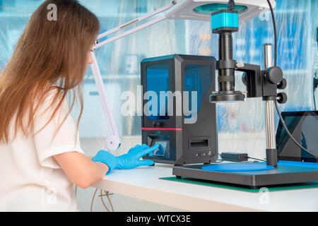 Lavoratore di sesso femminile nel controllo di resina LCD / DLP / SLA stampante 3D nel laboratorio di tecnologia Foto Stock