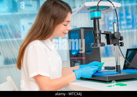 Lavoratore di sesso femminile nel controllo di resina LCD / DLP / SLA stampante 3D nel laboratorio di tecnologia Foto Stock