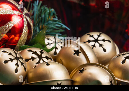 In prossimità di una ciotola piena di golden Jingle Bells con uno schema a fiocco di neve e un rosso con oro glitter ornamento palla di fuoco selettivo con spazio di copia Foto Stock