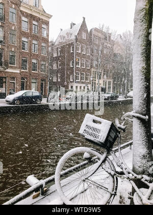 Biciclette nevoso sul ponte nel centro della città Amsterdam Paesi Bassi. La bufera di neve in inverno nei Paesi Bassi. Biciclette coperto da neve su un ponte. Foto Stock