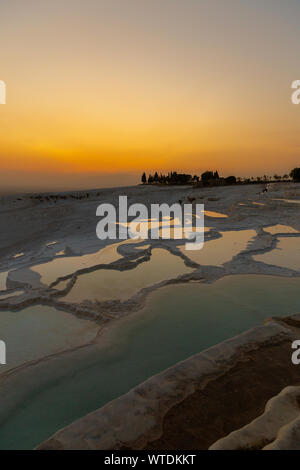 Tramonto su travertini di Pamukkale - Castello di Cotone - Palazzo di cotone Turchia con bellissimi colori e riflessi su acqua piscine Foto Stock