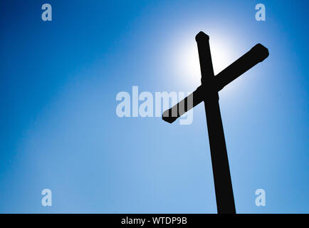 Silhouette fotografia di una croce con sun flare sul lato. Foto Stock