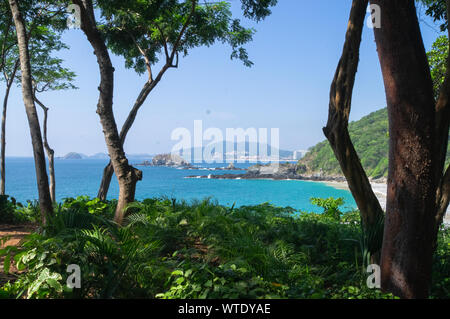 Bella e soleggiata spiaggia di Ixtapa zihuatanejo attraverso gli alberi e piante Foto Stock