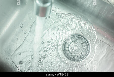 Aprire il rubinetto versare acqua nel lavello. Foto Stock