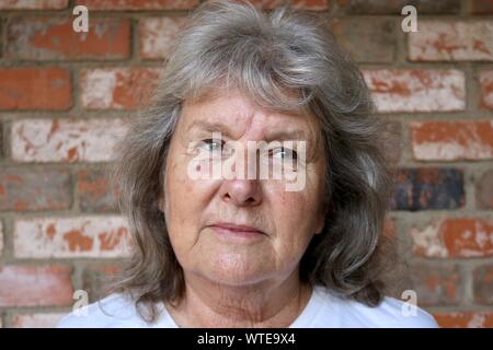 Ritratto di un pelo grigio donna che guarda lontano con il dubbio nei suoi occhi Foto Stock
