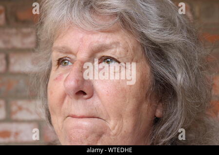 Ritratto di una donna senior con rinserrata labbra e un sguardo triste Foto Stock