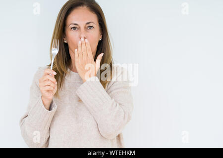 Medio Evo Woman holding argento metallico a forcella su sfondo isolato coprono la bocca con la mano sconvolto con vergogna per errore, espressione di paura, paura mi Foto Stock