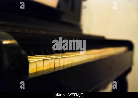 Chiudere l'immagine in prospettiva di vecchi tasti di pianoforte con profondità di campo ridotta. Messa a fuoco selettiva. Foto Stock