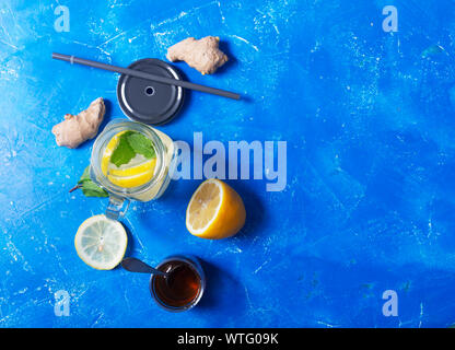 Lo zenzero acqua in un barattolo di vetro con limone e miele su uno sfondo blu con spazio di copia Foto Stock