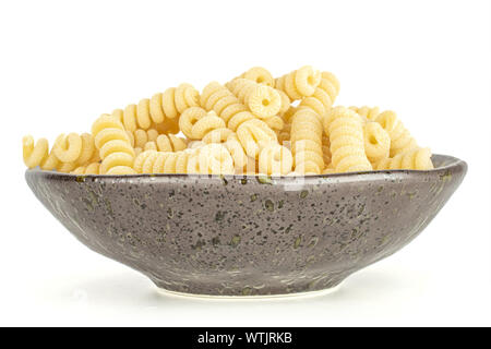 Sacco di intere fresche Materie pasta fusilli bucati su grigio piastra ceramica isolata su sfondo bianco Foto Stock