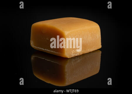 Un dolce intero golden caramella isolato sul vetro nero Foto Stock
