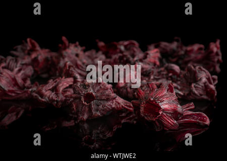 Sacco di tutto rosso dolce hibiscus candita isolato sul vetro nero Foto Stock