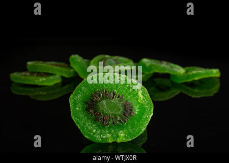 Sacco di fette di dolci verdi canditi di kiwi isolato sul vetro nero Foto Stock