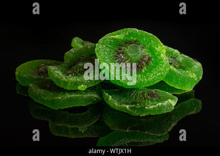 Sacco di fette di dolci verdi canditi di kiwi isolato sul vetro nero Foto Stock