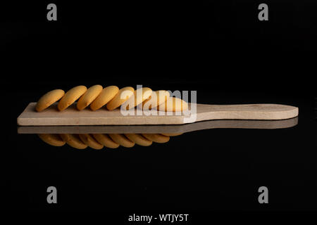 Gruppo di otto tutto il dolce e dorato biscotto di spugna sul piccolo tagliere di legno isolata sul vetro nero Foto Stock