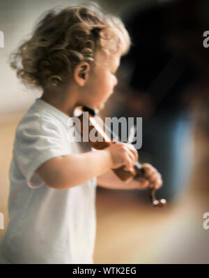 Il Toddler boy riproduzione di un violino in miniatura Foto Stock