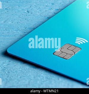 Closeup macro di un blu di credito contactless card chip su un blu sullo sfondo di legno Foto Stock