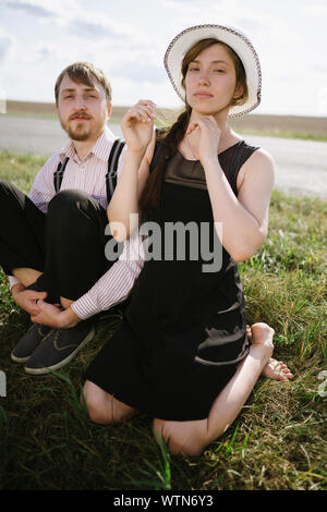 Giovane seduto vicino a una strada di campagna Foto Stock