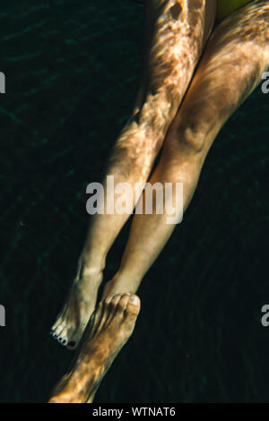 Gambe di anonimo a piedi nudi giovane sotto tranquille acque del Cenote Foto Stock