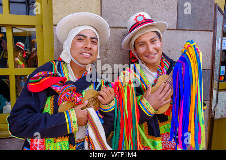 Ritratto di due giovani uomini, musicisti azienda gli strumenti a corda indossando il tradizionale abbigliamento peruviana e sorridente, Cusco, Perù. Foto Stock