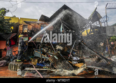 Pechino, Filippine. Undicesimo Sep, 2019. Un vigile del fuoco tenta di mettere fuori un incendio in una zona residenziale a Manila nelle Filippine, Sett. 11, 2019. Tre persone sono morte, tra cui due bambini di età compresa tra quattro e cinque, e altri due feriti in un incendio che ha colpito una zona residenziale nelle Filippine " capitale Manila mercoledì, l'ufficio locale di protezione antincendio detto. Credito: Rouelle Umali/Xinhua/Alamy Live News Foto Stock