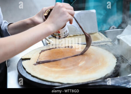 Berlino, Germania. Decimo Sep, 2019. Un membro del personale di strisci crema di cioccolato su un quasi finito crêpe in una fase di stallo a Berlino, capitale della Germania, il 7 settembre 10, 2019. Sebbene nata in Francia, crêpe è stato uno dei più famosi stuzzichini in Germania. Credito: Shan Yuqi/Xinhua/Alamy Live News Foto Stock