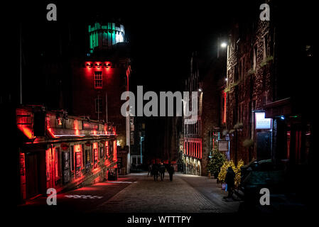 Edimburgo, Scozia, 13 dicembre 2018: la gente camminare lungo il Victoria St. A NOTTE Circondato da colorati edifici illuminati. Miscela di luce cruda Foto Stock