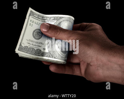 Un maschio nero consegna a mano su un batuffolo di piegato US Dollar banconote su un sfondo isolato Foto Stock