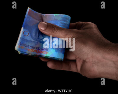 Un maschio nero consegna a mano su un batuffolo di piegato Swiss franc banconote su un sfondo isolato Foto Stock