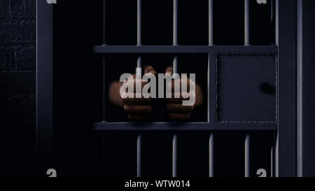 Un primo piano di una fioca carcere cella di contenimento porta con una coppia di neri africani tenendo le mani sulle barre Foto Stock