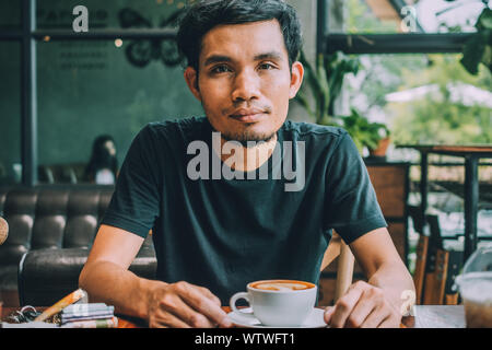 Uomo seduto in un coffee shop per bere il caffè in tempo Foto Stock