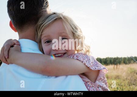 Ritratto di una giovane ragazza essendo portato da suo padre al tramonto Foto Stock