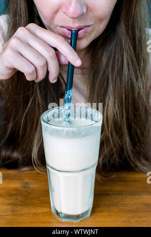 Giovane donna anonima frullato di bevande con paglia Foto Stock
