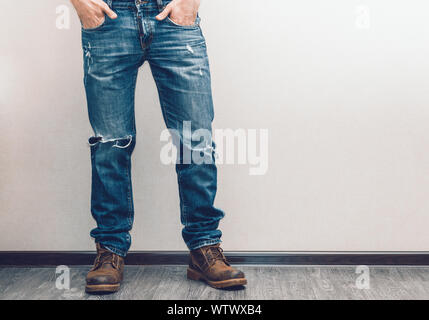 Moda giovane uomo per le gambe in jeans e stivali sul pavimento in legno Foto Stock