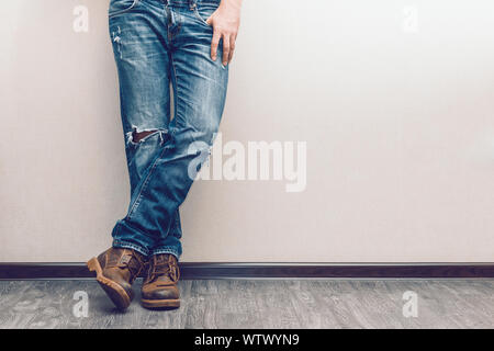 Moda giovane uomo per le gambe in jeans e stivali sul pavimento in legno Foto Stock