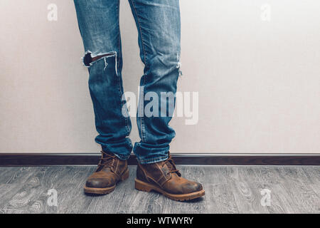 Moda giovane uomo per le gambe in jeans e stivali sul pavimento in legno Foto Stock