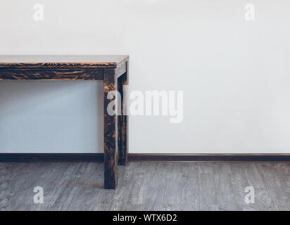 Parte di svuotare tavolo in legno nella camera sopra la parete di luce con spazio vuoto Foto Stock