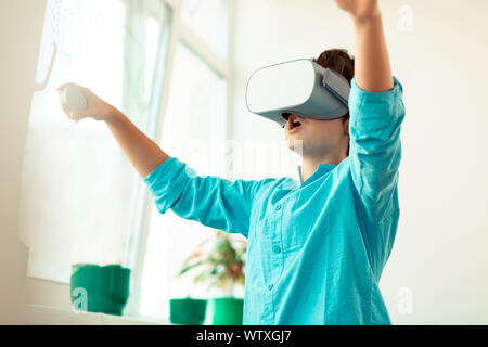 Emozionato schoolboy giocando giochi virtuali in aula. Foto Stock