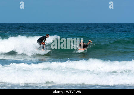 Sables D o Les Pins, Bretagne / Francia - 20 agosto 2019: Surfer il taglio di un altro surfer cattura un'onda nell'Oceano Atlantico sulla costa di Brit Foto Stock