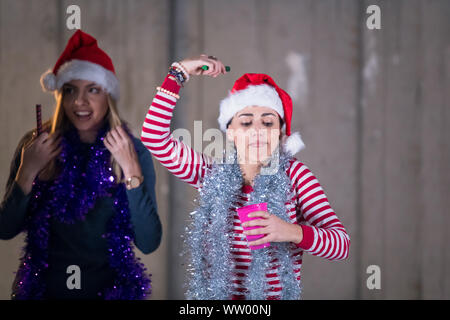 Gruppo multietnico di giovani felici informali di lavoro persone che ballano con botti e divertirsi mentre festeggia capodanno nella parte anteriore della parete di cemento Foto Stock