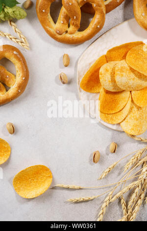 Assortimento di vari spuntini di birra - salatini, patatine e pistacchi su sfondo grigio chiaro con copia spazio. Foto Stock