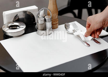 Ristorante cameriere serve una tabella, close-up. Il cameriere serve il vuoto stoviglie, impostazione tabella. La cameriera mette la forcella, imposta la tabella Foto Stock