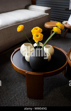 Bouquet di roselline (Ranunculus asiaticus) in un vaso nero. Fiori di colore giallo all'interno. Foto Stock