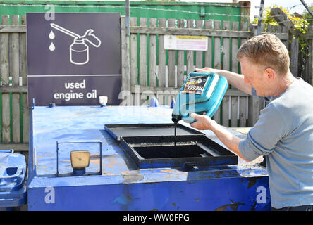 L'uomo versando olio motore usato nella tramoggia di riciclo al consiglio il riciclaggio Centre Regno Unito Foto Stock