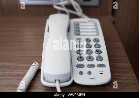 Vintage bianco telefono con battoms grigio su un tavolo marrone in hotel. Foto Stock