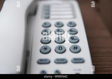 Vintage bianco telefono con battoms grigio su un tavolo marrone in hotel. Foto Stock